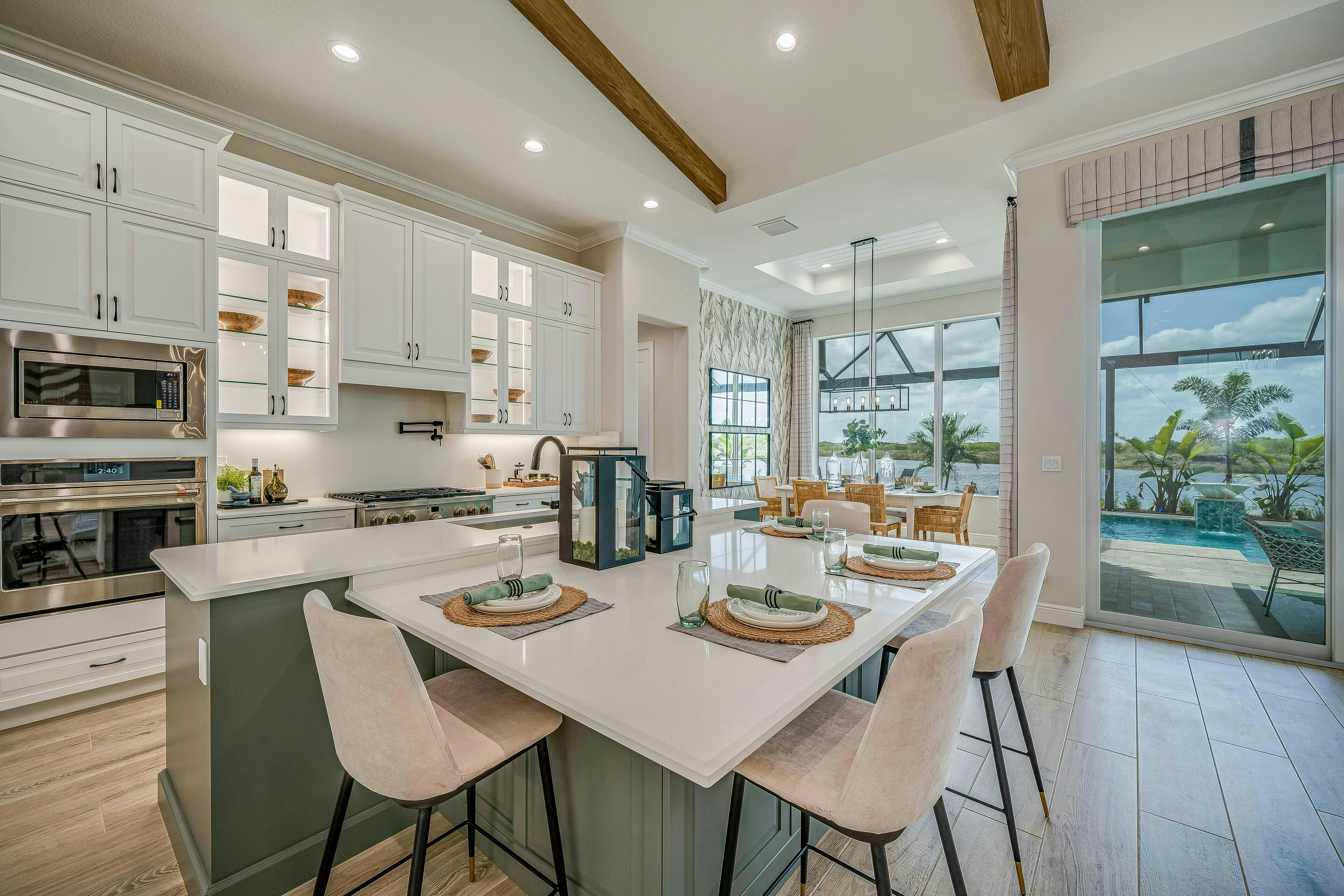 Expansive island with green cabinets and lowers seating, white wall cabients with glass doors