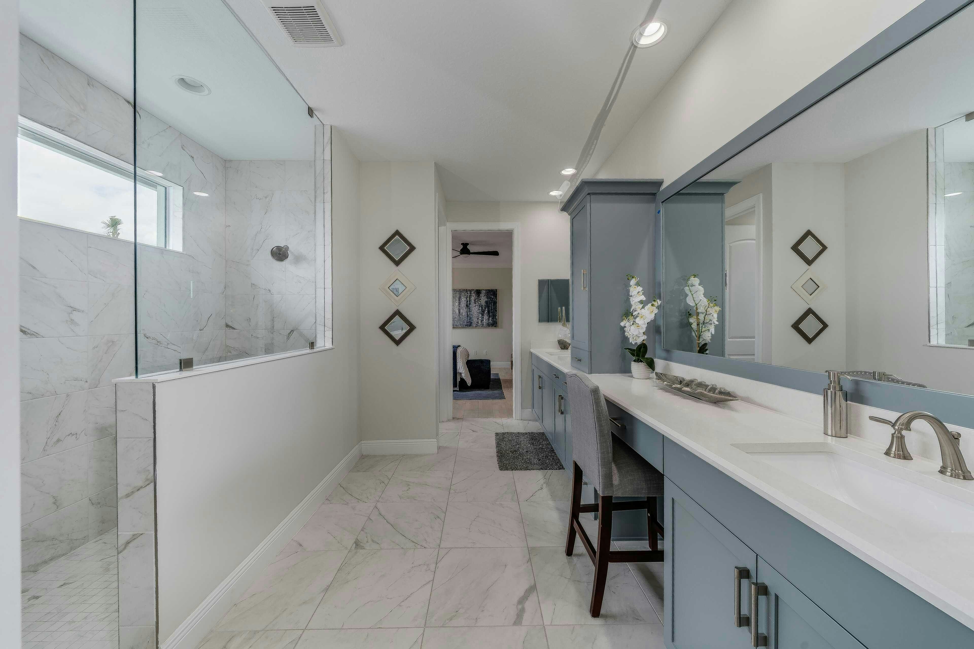 Master bath split vanity with view of walk-in shower and large tile flooring