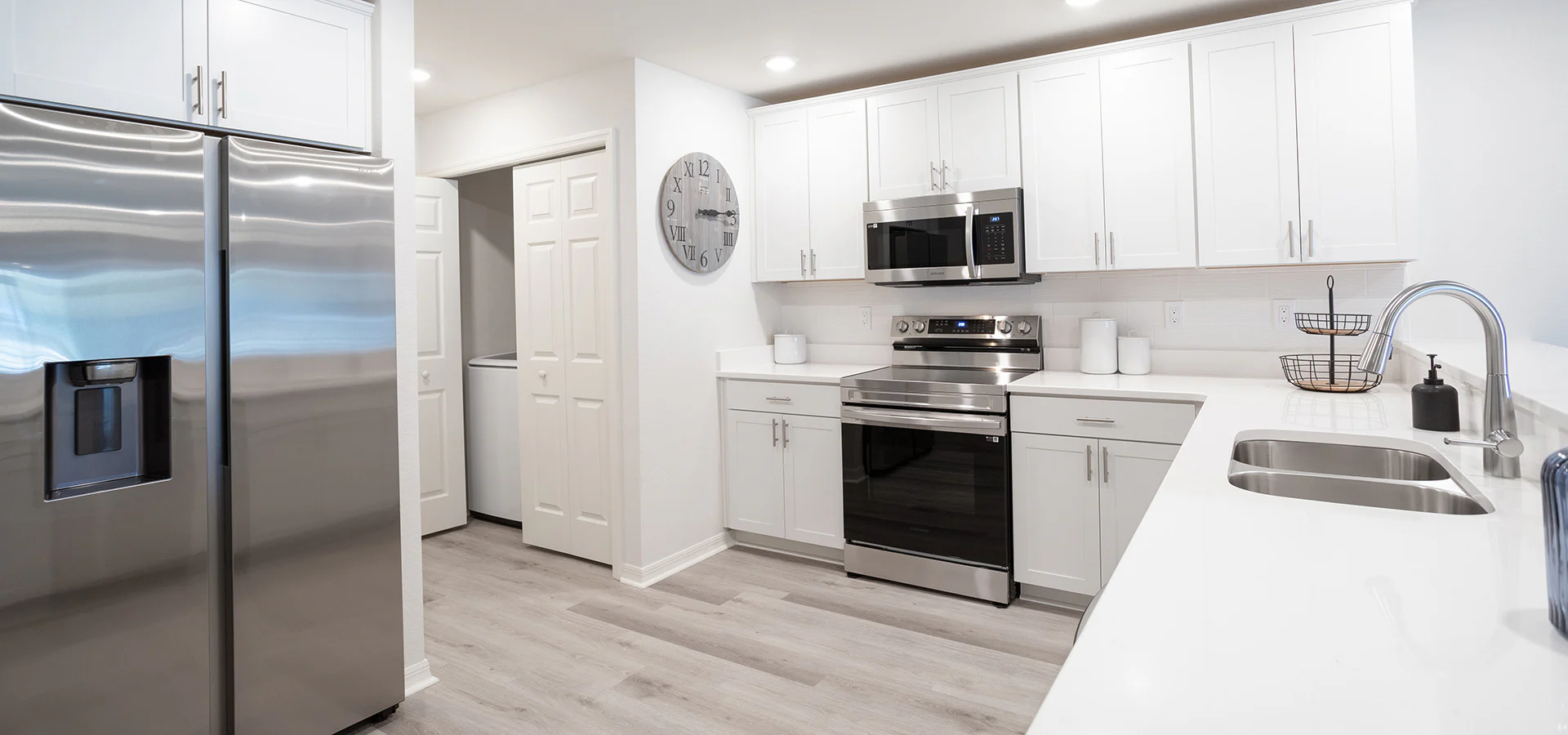 Bright kitchen with white cabinets, quartz counters, and stainless steel.