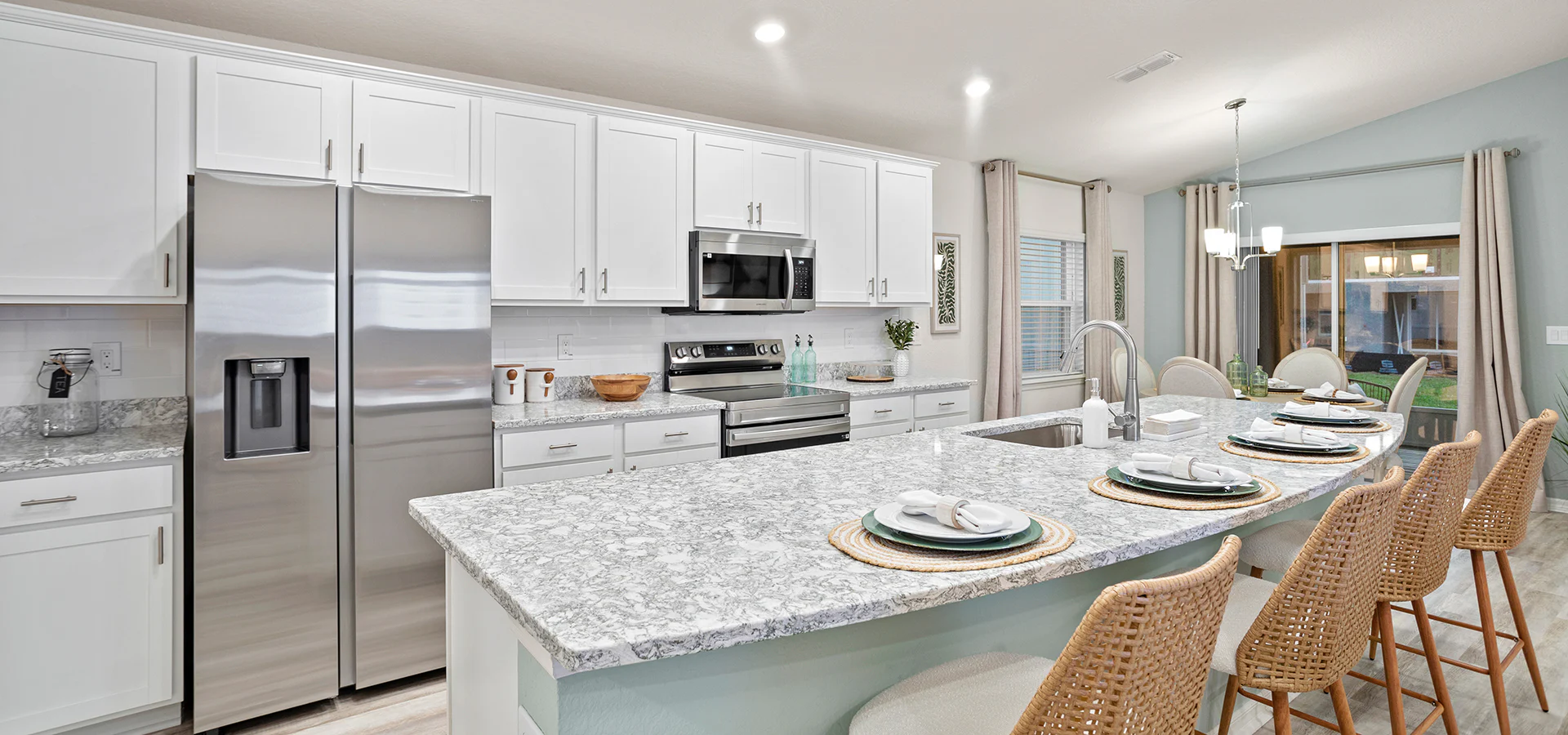 Bright, open kitchen with white cabinets, quartz counters, and a large island