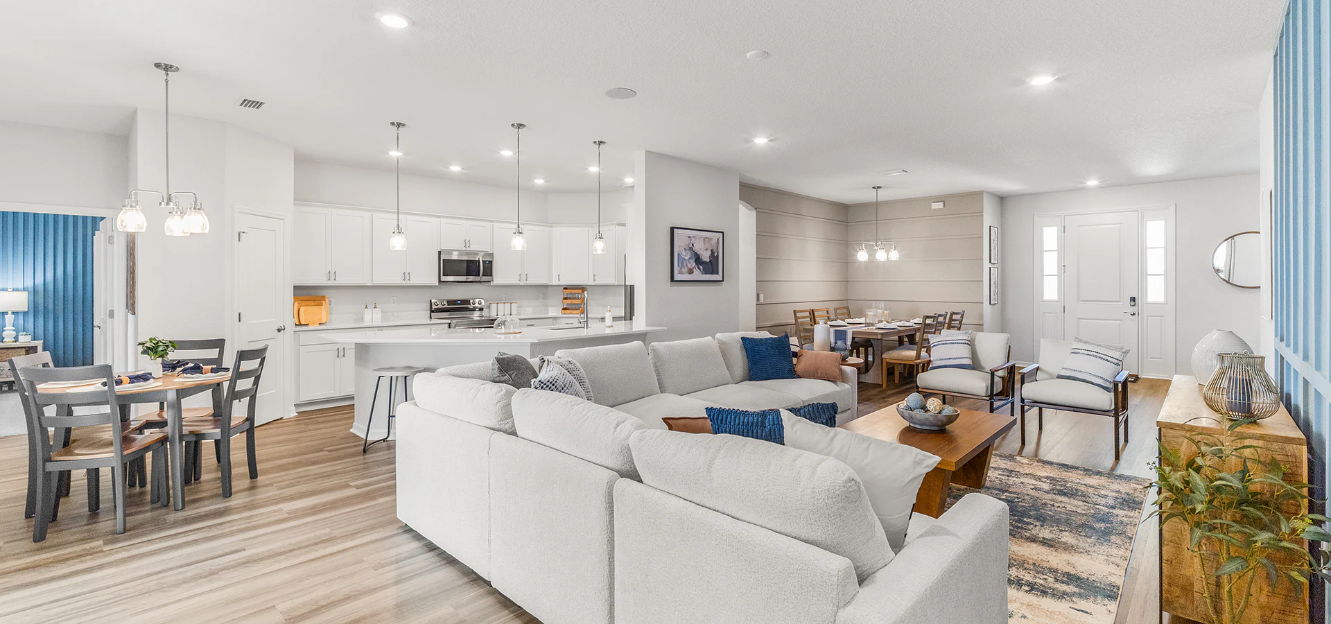 Bright and open living area with white cabinets, blue accents, and light colored LVP flooring