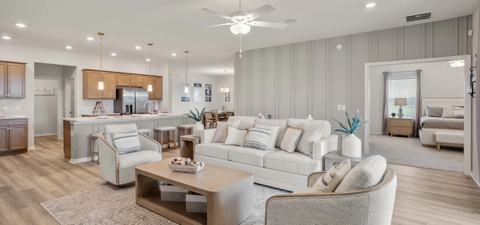 Open-concept living area with neutral toned furniture and wood cabinets and floors