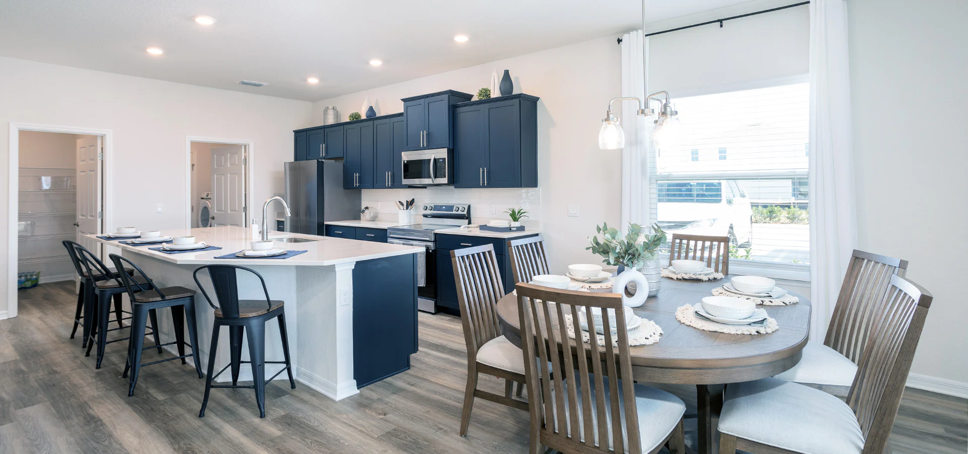 Open kitchen with blue cabinets, a large island, quartz counters, and sunny in-kitchen dining space.