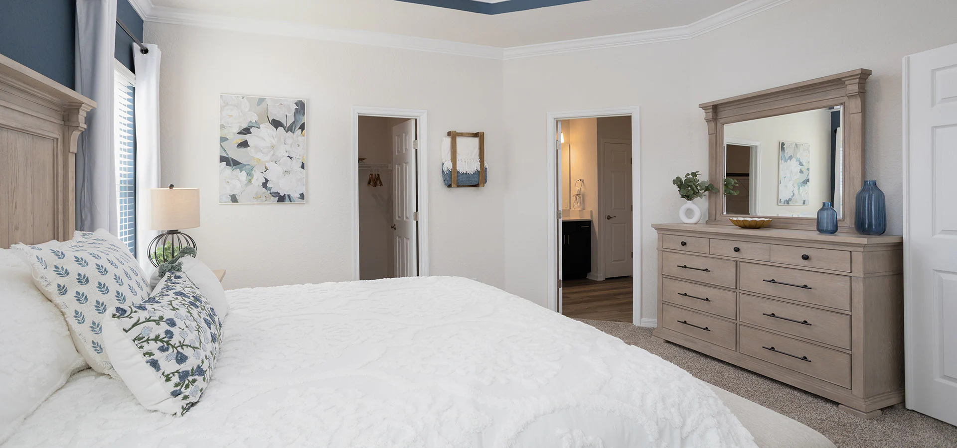 A large bedroom with a calming blue decor and crisp white linens