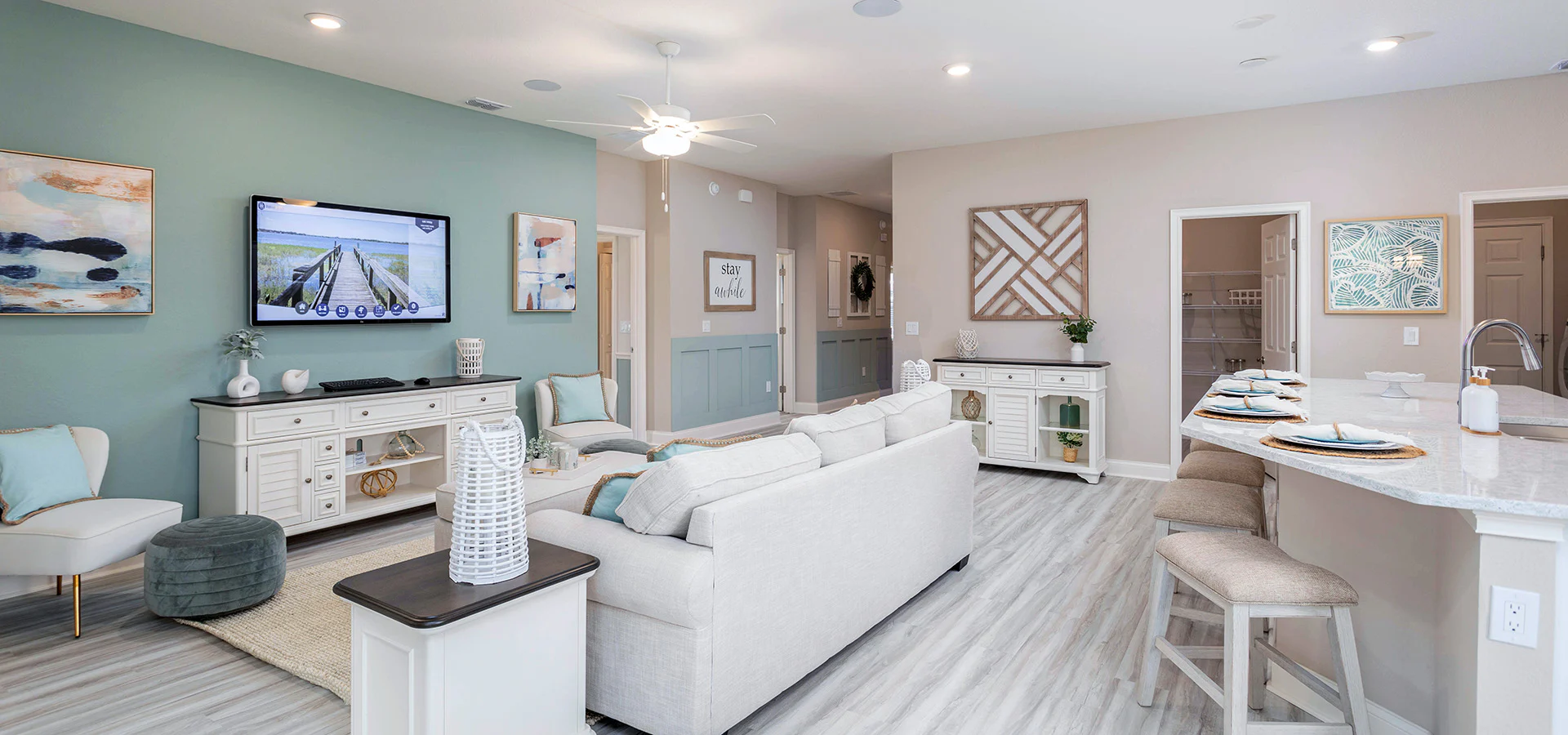 Living room with light colored wood flooring and furniture. and a mint green accent wall