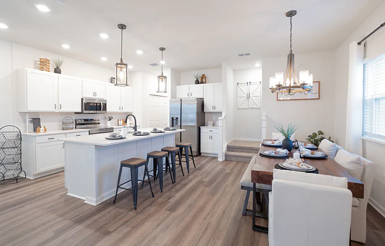 Bungalow kitchen in St. Cloud, FL with wood flooring, white cabinets, and table and island dining spaces.