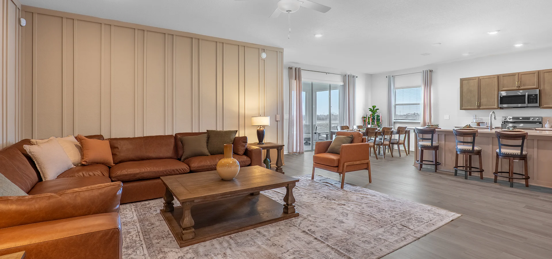 Open living area in the Monroe by Highland Homes, featuring a large leather sectional, side chairs, and trim accent wall.